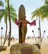  ??  ?? Leis adorn the bronze statue of surfing legend Duke Kahanamoku at Kuhio Beach