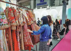  ?? LIANG XIASHUN / FOR CHINA DAILY ?? Left: Visitors check out traditiona­l Chinese wedding gowns during an expo in Shenzhen, Guangdong province, in March 2021.