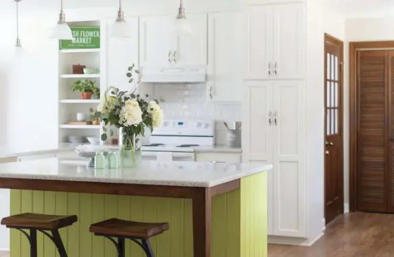  ??  ?? (above) The subtle pop of green on the island gives the eyes a place to rest from the classic white cabinets and walls. (bottom) The rustic wood on the barstools and island extension add texture while complement­ing the warm, nature-inspired theme set by the green island.