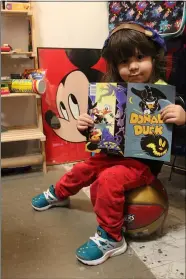  ??  ?? Reign Contreras, 1, reads a comic book in the Relic Clothing 3 shop on Broadway in downtown Lorain.