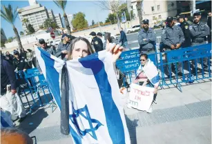  ?? (Baz Ratner) ?? A PROTESTER HOLDS an Israeli flag with a black ribbon tied to it at a demonstrat­ion in support of Sgt. Elon Azaria outside a military court in Tel Aviv yesterday.