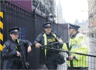  ?? FRED CHARTRAND/THE CANADIAN PRESS ?? Police officers armed with automatic weapons stand guard at blocked street leading to Parliament Hill in preparatio­n for Canada Day celebratio­ns.