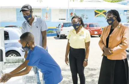  ??  ?? Young Tajae Brown washes his hands at the newly constructe­d handwashin­g station at the entrance to Ocho Rios Primary School in St Ann whil (from left) Phillip Brown, Tajae’s father; Sandals Foundation Public Relations Manager Patrice Gilpin; and principal at Ocho Rios Primary School, Suzette Barneswils­on, look on.