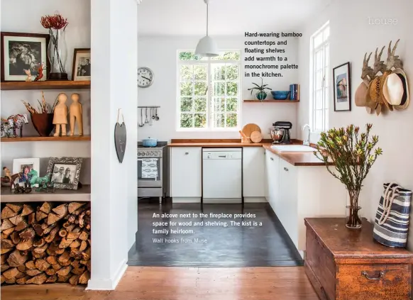  ??  ?? Hard-wearing bamboo countertop­s and floating shelves add warmth to a monochrome palette in the kitchen. An alcove next to the fireplace provides space for wood and shelving. The kist is a family heirloom.
Wall hooks from Muse