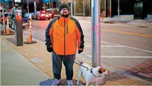  ?? [PHOTO BY SARAH PHIPPS, THE OKLAHOMAN] ?? Cody Lusnia, with his dog Rip, stands next to a light pole in downtown Oklahoma City. Lusnia mapped 419 nonworking lights downtown and in Midtown, prompting action by the city to restore them to service.