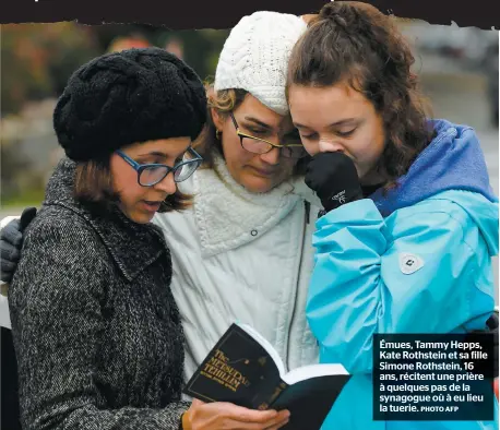  ??  ?? Émues, Tammy Hepps, Kate Rothstein et sa fille Simone Rothstein, 16 ans, récitent une prière à quelques pas de la synagogue où à eu lieu la tuerie.