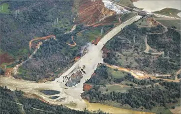  ?? Marcus Yam Los Angeles Times ?? WATER FLOWS down the Oroville Dam’s damaged main spillway Feb. 21. The earthen emergency spillway, seen to the left, also failed due to erosion. The spillways will require $275 million in repairs before Nov. 1.