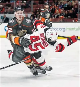  ?? Jae C. Hong Associated Press ?? THE DEVILS’ Sami Vatanen loses his balance as he fires a shot amid defensive pressure from the Ducks’ Josh Manson during the first period Sunday.