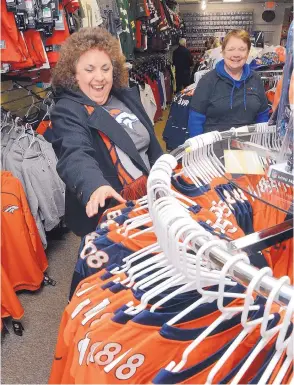  ?? JIM THOMPSON/JOURNAL ?? Donna Casaus, who says she has been a Broncos fan for 25 years, looks for a jersey as she gets help from Brenda Steward on Friday at the House of Football store.