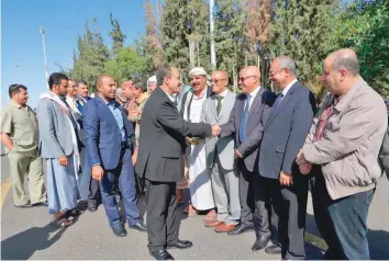 ?? — AFP ?? Members of Ansar Allah delegation returning from peace talks in Sweden shake hands with supporters upon their arrival at Sanaa Internatio­nal Airport in the Yemeni capital.