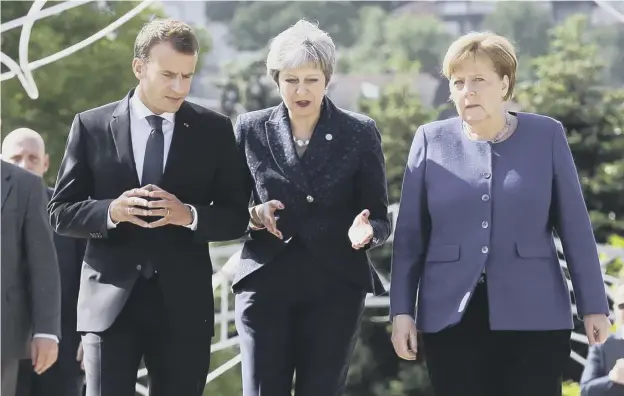  ??  ?? 0 French president Emmanuel Macron, Theresa May and German Chancellor Angela Merkel speak following a meeting on the sidelines of the EU- Western Balkans Summit