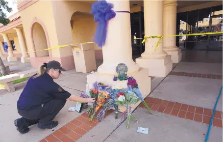  ?? ADOLPHE PIERRE-LOUIS/JOURNAL ?? Danielle Bell, a security guard at Clovis High School, puts flowers at a memorial for the victims of the Aug. 28 mass shooting at the ClovisCarv­er Public Library.