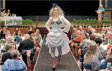  ?? LAWRENCE GULLERY ?? This high tea inspired gown was the overall winner, designed by Fiona Norman and modelled by her daughter, Aislinn. It is comprised of a cropped embroidere­d bolero, lace fitted top, corset decorated with silver cutlery, a short many-layered bustled...