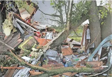  ?? JOURNAL SENTINEL FILES ?? A firefighte­r searches the debris of a house looking for survivors after a tornado ripped through a neighborho­od north of Stoughton on Aug. 18, 2005. Firefighte­rs found a cat and dog alive while searching the rubble. No humans were home when the tornado hit.