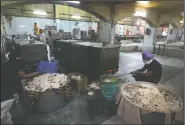  ??  ?? Sikh volunteers take cooked chapatis out of a machine.