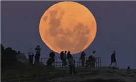  ?? ?? People watch as the ‘super flower blood moon’ rises over Bondi Beach in Sydney on 26 May, 2021. Guardian Australia’s picture editor explains how to photograph the partial lunar eclipse of the November 2021 full moon, whether you’re using a phone or DSLR camera, and the best settings to use. Photograph: Anadolu Agency/Getty Images