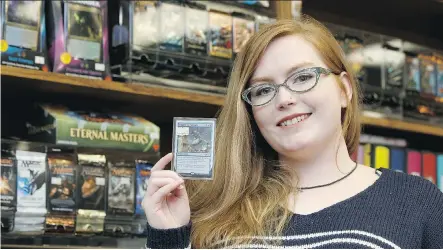  ?? IAN KUCERAK ?? Kim Lewis of Warp One Comics holds a Magic: The Gathering card at the store in Edmonton Thursday. The game is a big target for thieves.