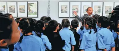  ?? JIANG DONG / CHINA DAILY ?? Song Feijun (facing front), a grandson of late Chinese painter Feng Zikai, gives a guided tour to children visiting the ongoing exhibition of Feng’s works at the National Art Museum of China through Nov 4.