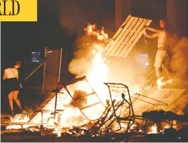  ?? NICHOLAS PFOSI/REUTERS ?? A protester fuels a fire barricade in Minneapoli­s in the aftermath of the police-custody death of George Floyd.