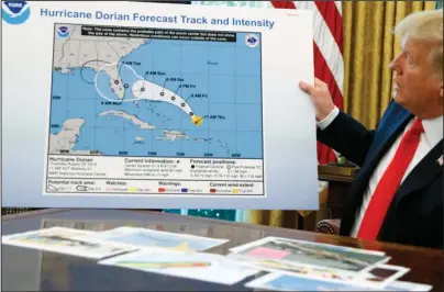  ?? The Associated Press ?? HURRICANE DORIAN: In this Sept. 4, 2019, file photo, President Donald Trump holds a chart as he talks with reporters after receiving a briefing on Hurricane Dorian in the Oval Office of the White House in Washington. Political pressure from the White House and a series of “crazy in the middle of the night” texts, emails and phone calls caused top federal weather officials to wrongly admonish a weather office for a tweet that contradict­ed Trump about Dorian in 2019, an inspector general report issued Thursday found.