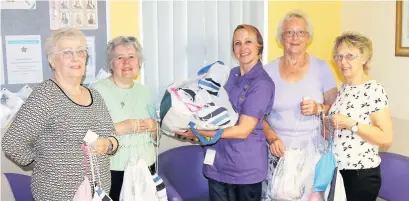  ??  ?? Bereavemen­t care nurse Erin Bolton (centre) receives comfort bags from All Saints Mothers Union members (from left) Mary O’Rourke, Margaret Sims, Christine Cairns and Hazel Cross