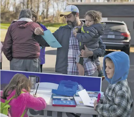  ?? BY LUKE CHRISTOPHE­R ?? Mathew Gries and daughter study a sample ballot at the Washington fire hall yesterday. More photos of the day on page A4.