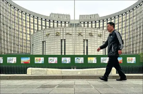  ?? ?? A pedestrian walks past the headquarte­rs of the PBOC in Beijing.