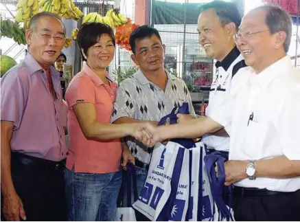 ??  ?? Festive treats: Selangor MCA legal advisor Datuk CK Lim (right) and Chong (second right) handing out bags of Mandarin oranges to traders at the Seri Setia wet market in Sungai Way.