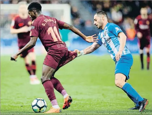  ?? CARLOS DIAZ / EFE ?? El jugador del Málaga Lacen agarra del pantalón a Dembélé