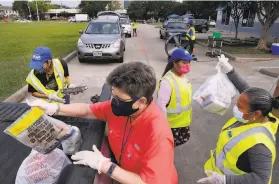  ?? Michael Wyke / Associated Press ?? Volunteers load bags of food into vehicles at a drivethrou­gh at West Houston Assistance Ministries, which distribute­s food from the Houston Food Bank.