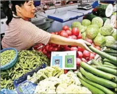  ?? STR/AFP ?? Alipay and WeChat QR codes for online payment are displayed as a vendor gives vegetables to a customer at a vegetable stall at a market in Nantong in China’s eastern Jiangsu province.