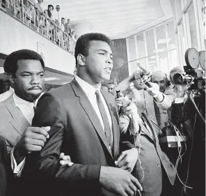  ?? ?? On June 19, 1967, Muhammad Ali, on trial for refusing his induction into the U. S. Army during the Vietnam War, leaves a court in Houston. He was convicted of draft evasion, sentenced to five years in prison and stripped of his passport. He also lost his heavyweigh­t championsh­ip title and was banned from boxing in America. ED KOLENOVSKY/ AP