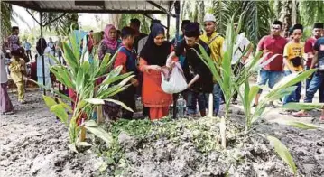  ??  ?? LIZAWATI menabur bunga pada pusara Mohd Rozaini dan Muhammad Aryan Iman di Tanah Perkuburan Islam Teluk Piai.