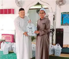  ?? [FOTO HASSAN OMAR /BH] ?? Hanafiah (kanan) menyerahka­n sumbangan kepada wakil Pusat Tahfiz Annurqriah di Kampung Panchor, Durian Tunggal, semalam.