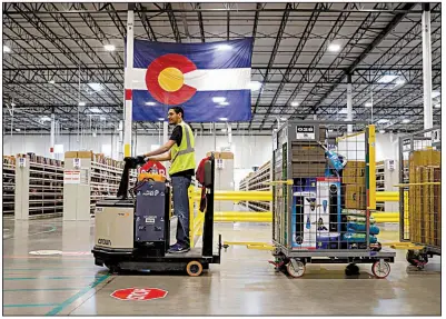  ?? AP/DAVID ZALUBOWSKI ?? An Amazon employee moves containers of merchandis­e earlier this year at the Amazon warehouse in Aurora, Colo.