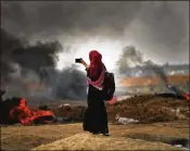  ?? SPENCER PLATT / GETTY IMAGES ?? A Palestinia­n woman documents the clash along the border fence with Israel as demonstrat­ions continue Monday in Gaza City. Israeli soldiers killed at least 52 Palestinia­ns and wounded more than 2,400.