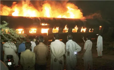  ?? (AP Photo/K.M. Chaudary) ?? People look at a burning passenger train in Shaikhupur­a, near Lahore, Pakistan, early Tuesday, March 28, 2017. Authoritie­s in Pakistan say a passenger train has collided with an oil tanker truck, killing at least one person and injuring others.