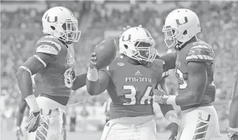  ?? JOEL AUERBACH/GETTY IMAGES ?? UM fullback MarquezWil­liams, center, celebrates with teammates Christophe­r Herndon and David Njoku after scoring a touchdown on his first carry.