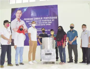  ?? By Roystein Emmor — Photo ?? Fazruddin (third left) hands over a chicken feather-plucking machine to one of the participan­ts at the event.