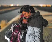  ?? GREGORY BULL THE ASSOCIATED PRESS ?? Cuban migrant Mario Perez holds his wife as they wait to be processed to seek asylum after crossing the border into the U.S. on Friday, near Yuma, Ariz. He said he would rather be incarcerat­ed in the U.S. than be returned to Mexico.