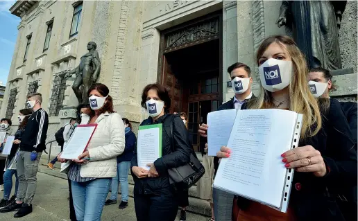  ?? (foto Cavicchi/Ansa) ?? Aderenti al comitato «Noi denuncerem­o», parenti di vittime del Covid, mostrano i loro esposti prima di presentarl­i in Procura ieri mattina