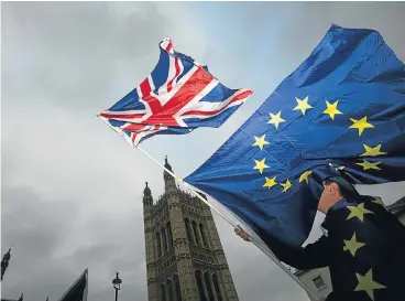  ?? /Reuters ?? Expensive divorce: An anti-Brexit protester waves EU and Union flags outside the Houses of Parliament in London on Tuesday. Surveys reports just out have revealed that Britain’s economy lags the EU as Brexit weighs on business and consumers.