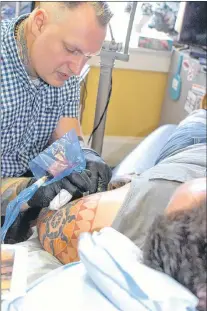  ?? ROSIE MULLALEY/THE TELEGRAM ?? Tattoo artist Dave Munro works on client Craig Rogers at his Trouble Bound Studio on Water Street in St. John’s. Munro has a two-year waiting list for clients.