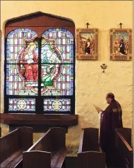  ?? Matthew Brown / Hearst Connecticu­t Media ?? The Rev. Jose Montoya, parochial vicar of St. Mary's Church, stands before one of the 14 Stations of the Cross as he reads a reflection inside the empty sanctuary of St. Benedict’s Church, while being recorded for a Good Friday Mass on April 10 in Stamford.