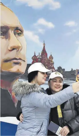  ?? STRINGER / EFE ?? Dos mujeres se hacen un selfi junto a un retrato de Putin en Donetsk.