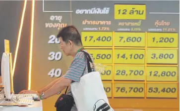  ?? SOMCHAI POOMLARD ?? A man browses investment and savings plans provided at SET in the City 2018.