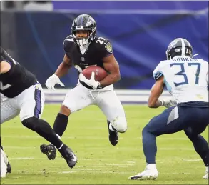  ?? Nick Wass / Associated Press ?? Baltimore Ravens running back J.K. Dobbins (27) runs with the ball against Tennessee Titans safety Amani Hooker (37) during the second half of an NFL game on Nov. 22 in Baltimore. Dobbins is one of more than a dozen Ravens on the COVID-19 list.