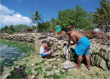  ??  ?? Photo ci-dessus : Photograph­ie publiée par le Secrétaria­t de la Communauté du Pacifique (CPS) montrant des habitants de l’atoll corallien Kiritimati, aux Kiribati, en train de construire une digue avec des blocs de corail pour se protéger contre la hausse du niveau de la mer due au réchauffem­ent climatique. En mai 2014, le président des îles Kiribati, Anote Tong, a acheté un terrain de 22 km2 aux Fidji pour que son peuple ait un refuge lorsque leurs 33 atolls éparpillés dans le Pacifique seront engloutis par la mer. (© AFP/CPS)