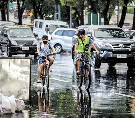  ?? PHOTOGRAPH BY YUMMIE DINGDING FOR THE DAILY TRIBUNE@tribunephl_yumi ?? Slippery when wet Philippine­s.
Bicycle riders endure wet road as Pag-asa declared on Friday the start of the rainy season in the