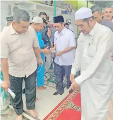  ??  ?? The viral photo which actually shows Shafie handing out money after Friday prayers at the Masjid Datuk Pangeran Galpam in Sandakan.